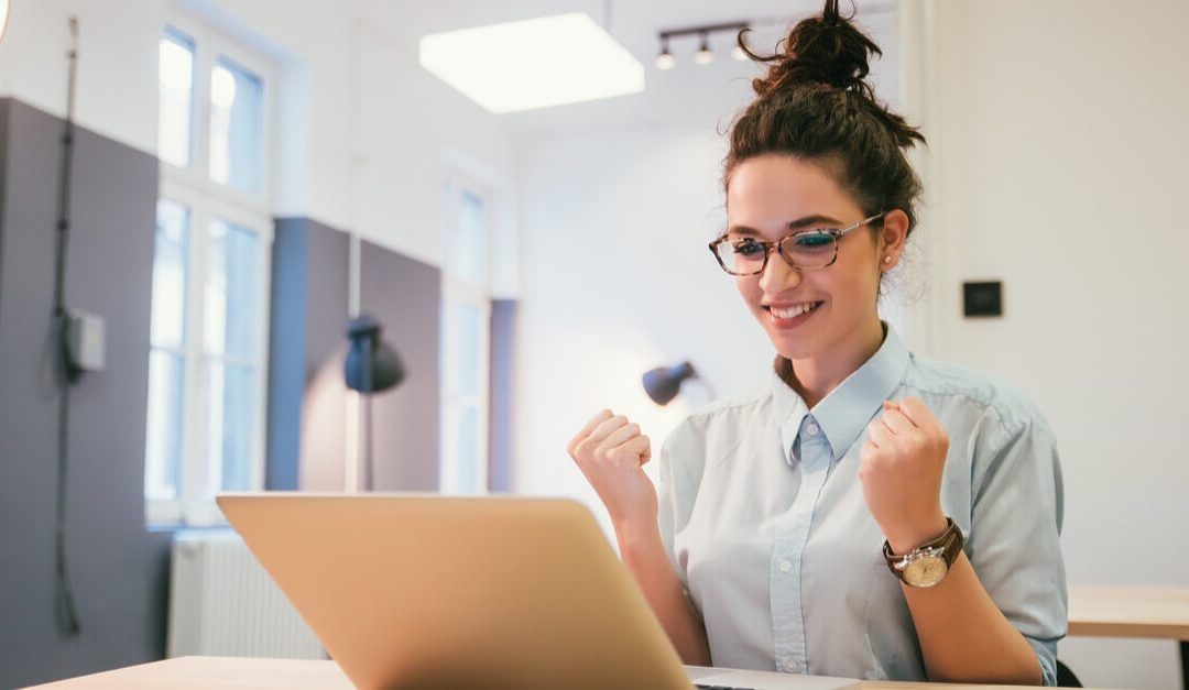 Woman celebrating while studying on laptop